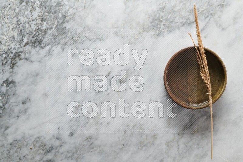 Wheat stalks on multicolored pottery oven plate on grey marble background