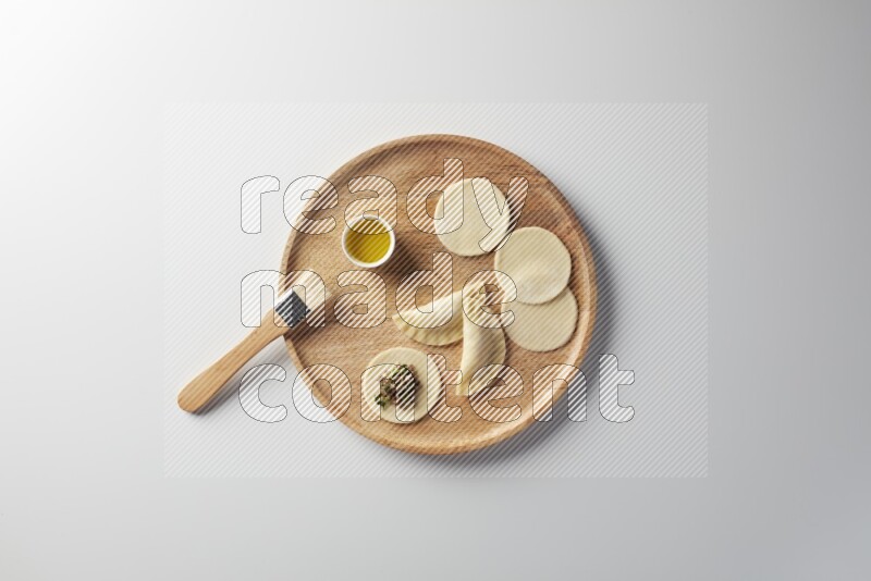 two closed sambosas and one open sambosa filled with meat while oil with oil brush aside in a wooden dish on a white background