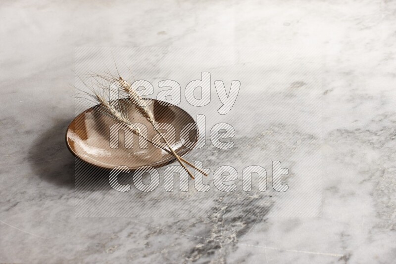 سنابل من القمح علي طبق فخاري متعدد الألوان علي خلفية من الرخام الرمادي