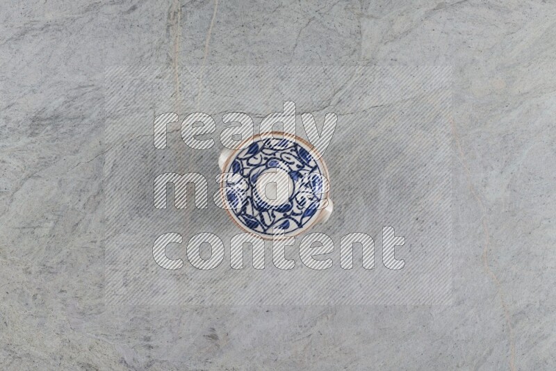 إناء فخاري متعدد الألوان مع غطائه على خلفية من الرخام الرمادي