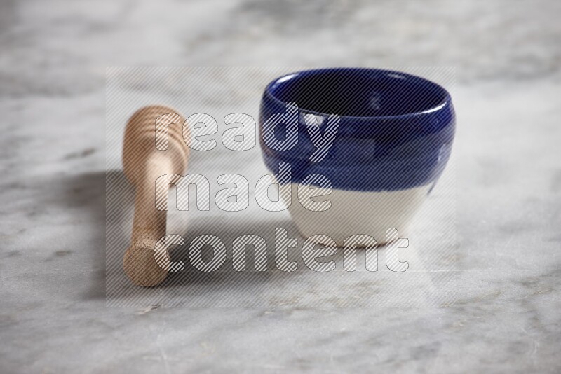 Multicolored pottery bowl with wooden honey dipper on the side on grey marble background