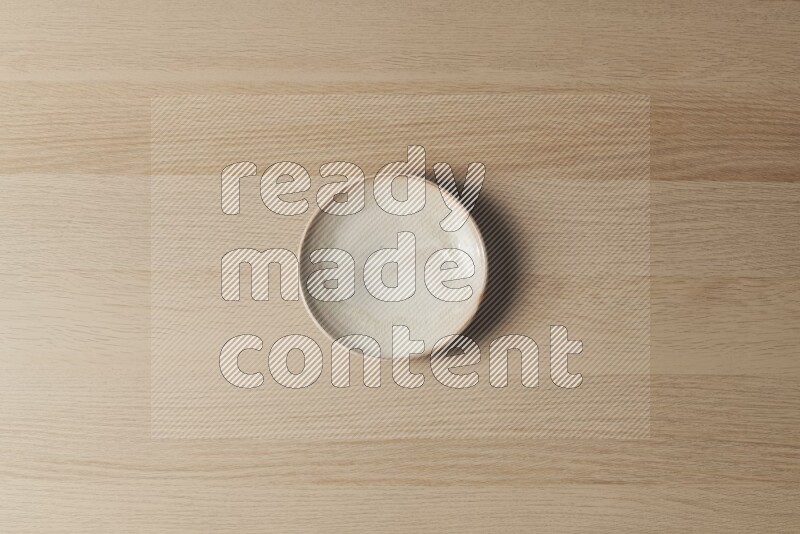 A beige pottery plate on light wooden background