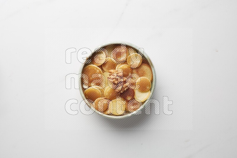 Top-view shot of walnut cereal pancakes in a round bowl on white background