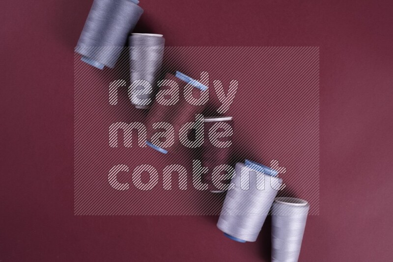 مجموعة من أدوات الخياطة والتفصيل رمادية اللون على خلفية حمراء