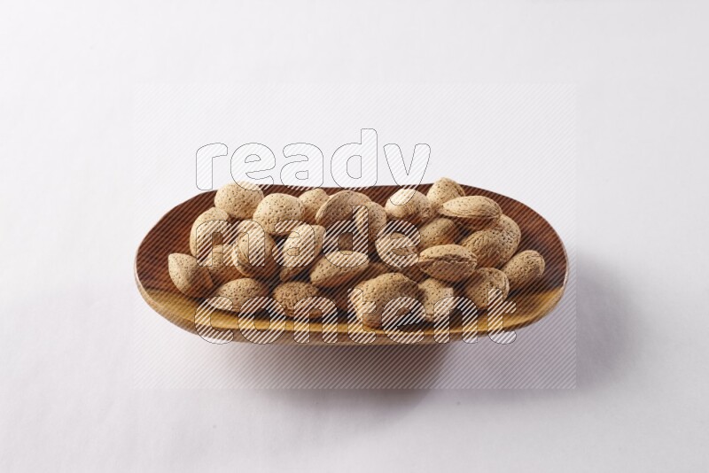 Almonds in a wooden plate on white background