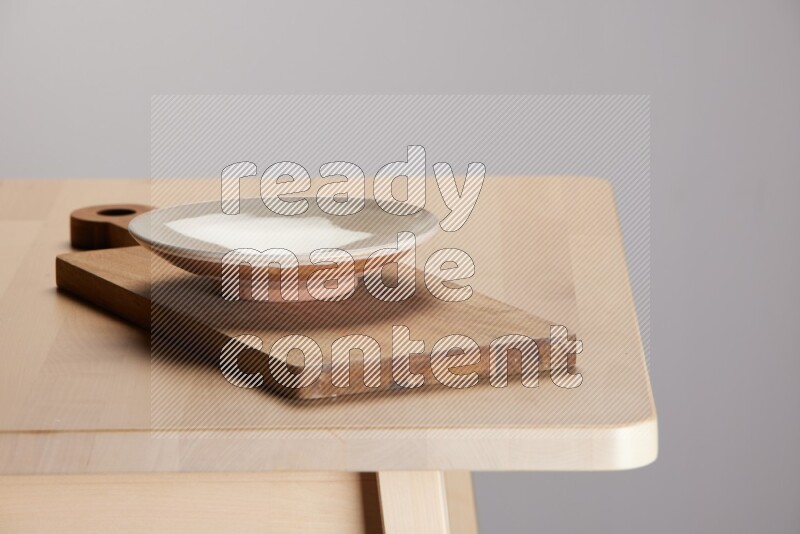 multi-colored pottery Plate placed on a  wooden rectangular cutting board on the edge of wooden table