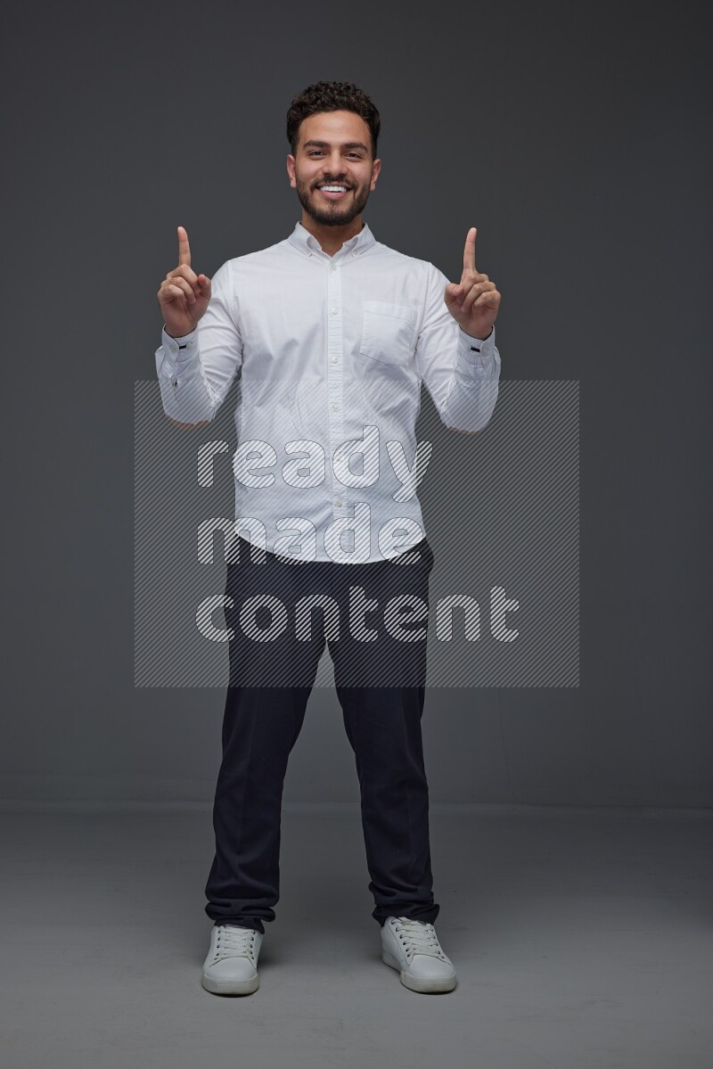A man wearing smart casual standing and making multi hand gestures eye level on a gray background