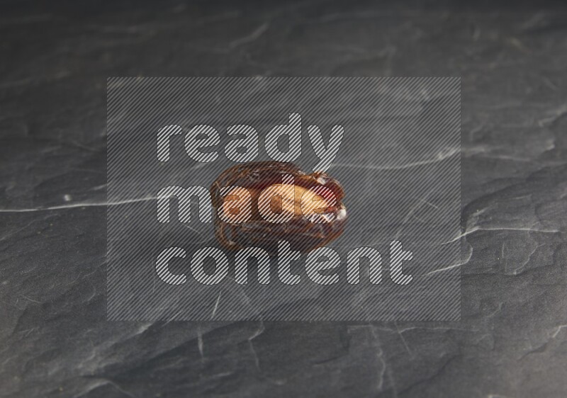 almond stuffed madjoul date on a black textured background