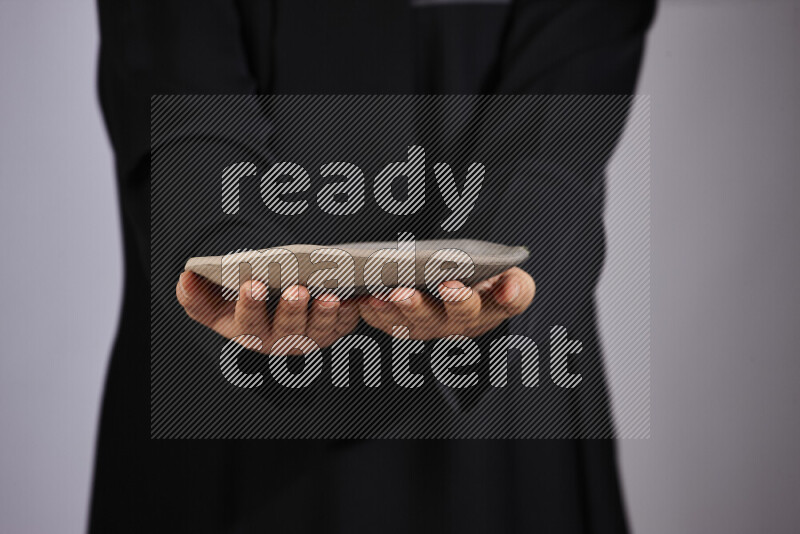 A woman in black abaya holding different pottery essentials in different positions
