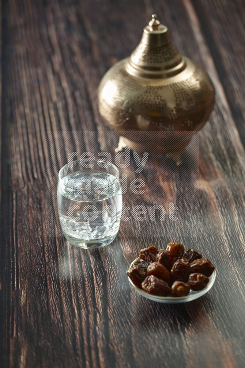 A golden lantern with different drinks, dates, nuts, prayer beads and quran on brown wooden background