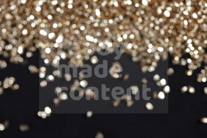 Gold shimmering fragments of glass scattered on a black background
