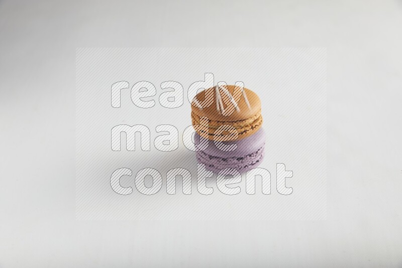 45º Shot of of two assorted Brown Irish Cream, and Purple Blueberry macarons on white background