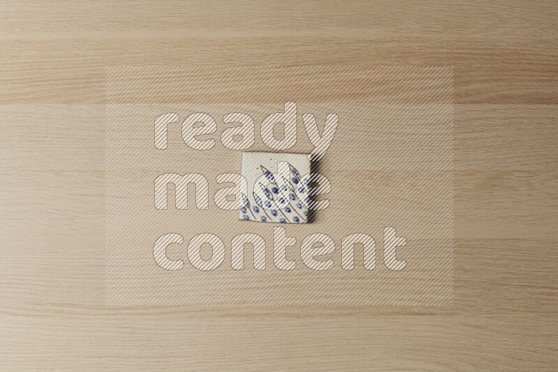 A decorative pottery coaster on light wooden background