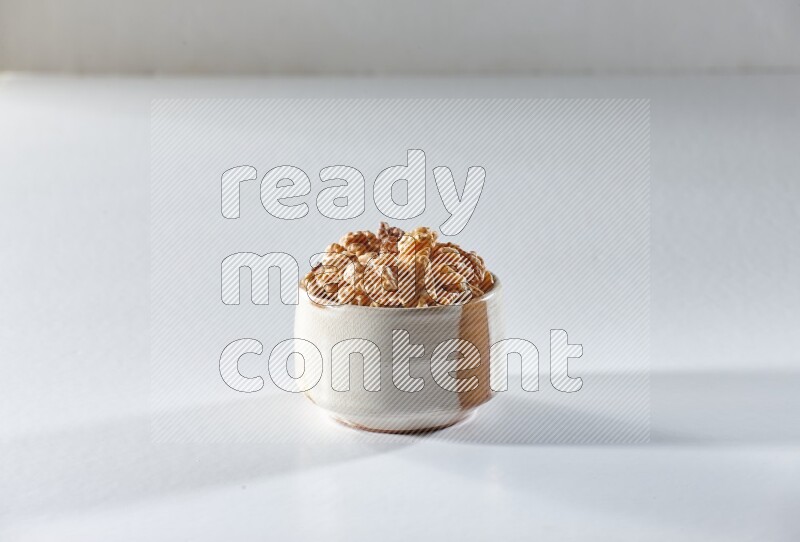 A beige ceramic bowl full of peeled walnuts on a white background in different angles