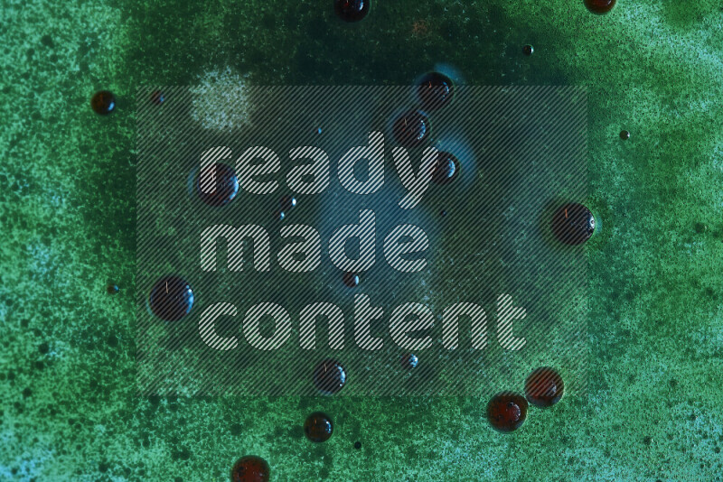 لقطات مقربة لقطرات ألوان مائية حمراء وخضراء على سطح الزيت على خلفية خضراء