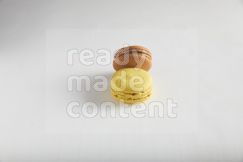 45º Shot of of two assorted Brown Irish Cream, and Yellow Lemon macarons on white background