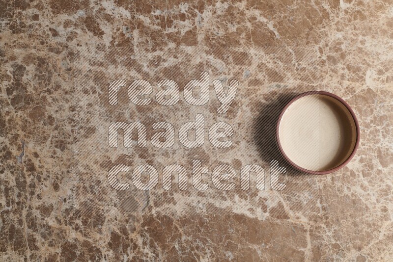 A beige pottery oven plate on beige marble background