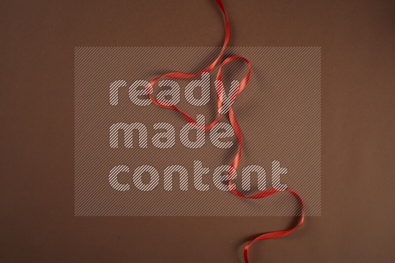 A red collection of sewing and tailoring tools arranged on a brown background
