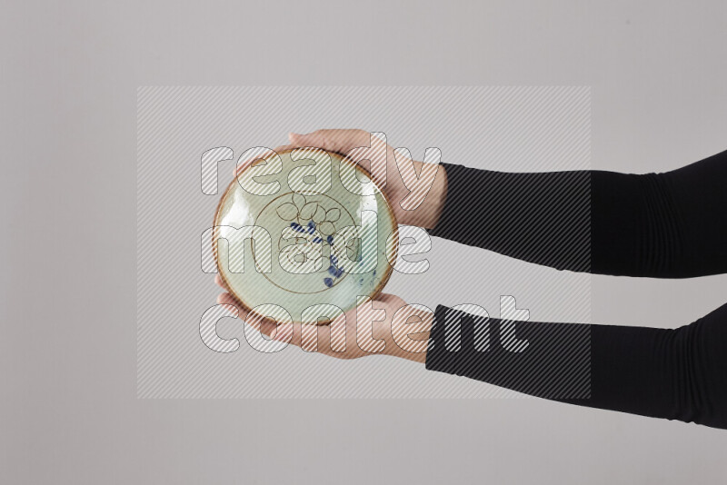 A woman in black abaya holding different pottery essentials in different positions