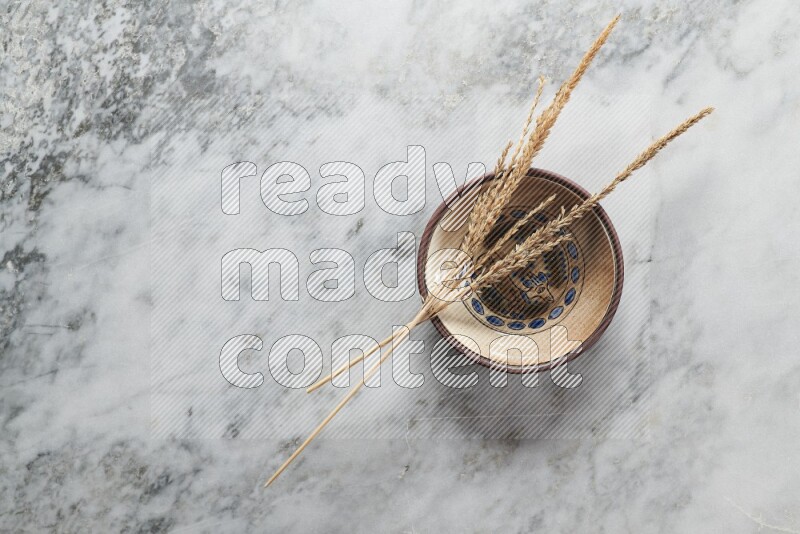 Wheat stalks on decorative pottery plate on grey marble background