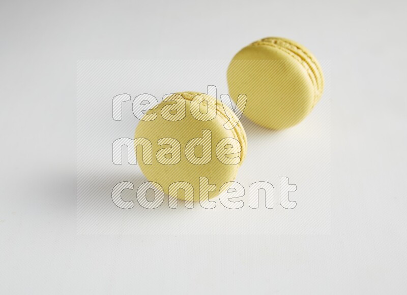 45º Shot of two Yellow Lime macarons on white background