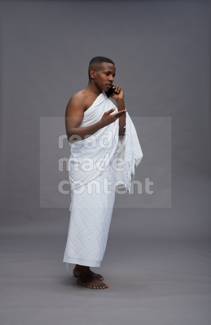 A man wearing Ehram Standing talking on phone on gray background