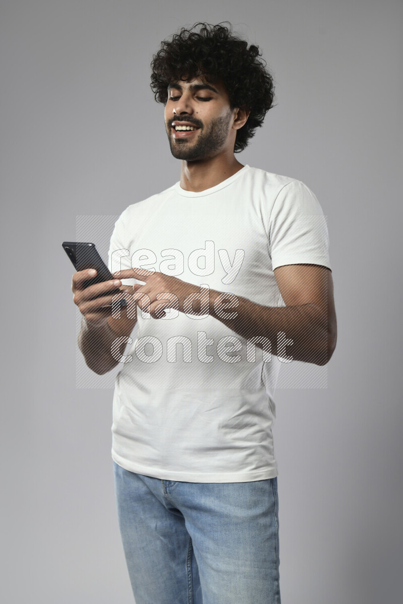 A man wearing casual standing and browsing on the phone on white background