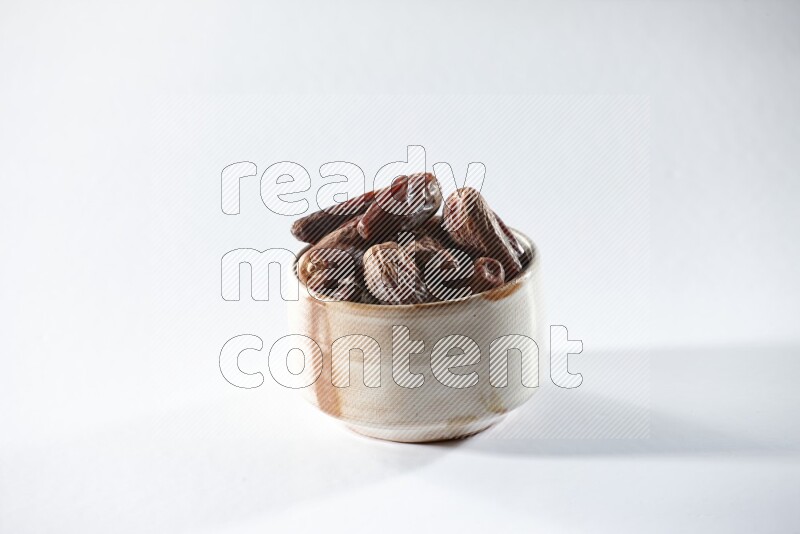 A beige ceramic bowl full of dried dates on a white background in different angles