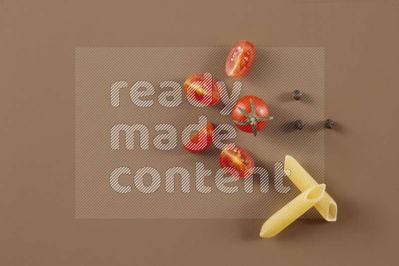 Raw pasta with different ingredients such as cherry tomatoes, garlic, onions, red chilis, black pepper, white pepper, bay laurel leaves, rosemary and cardamom on beige background