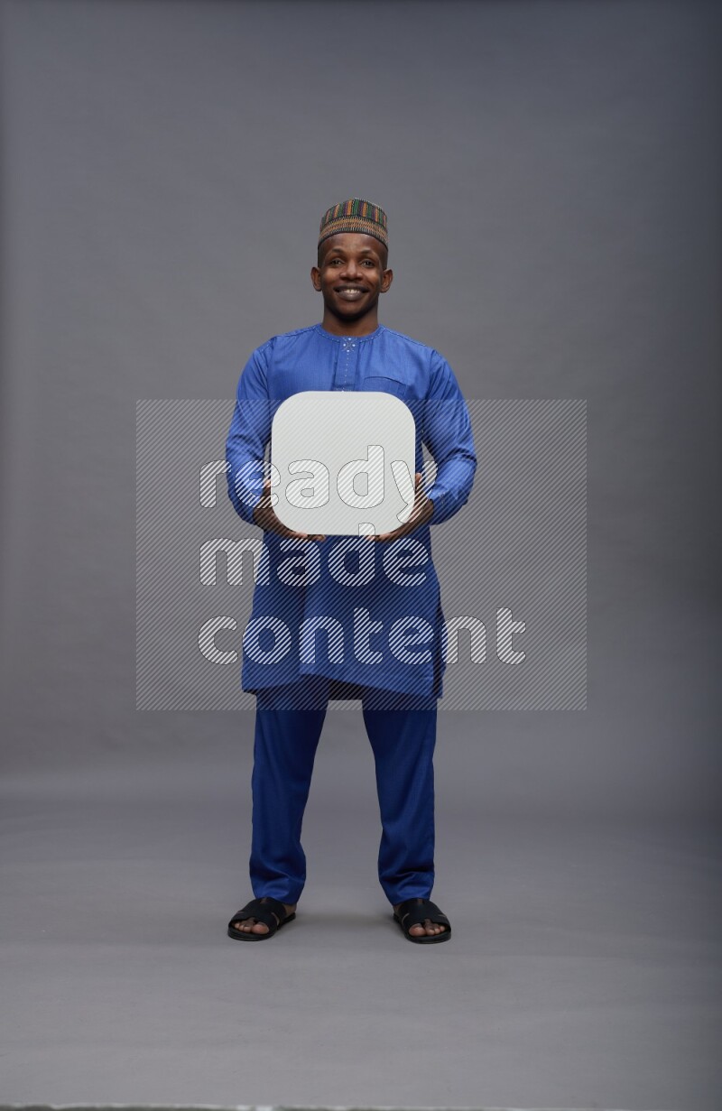 Man wearing Nigerian outfit standing holding social media sign on gray background