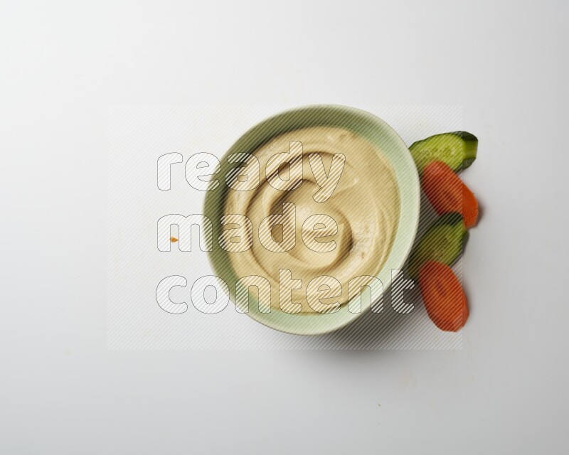 plain Hummus in a green plate on a white background