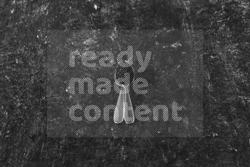 ملعقتان معدنيتان ممتلئتان ببذور حبة البركة علي خلفية سوداء