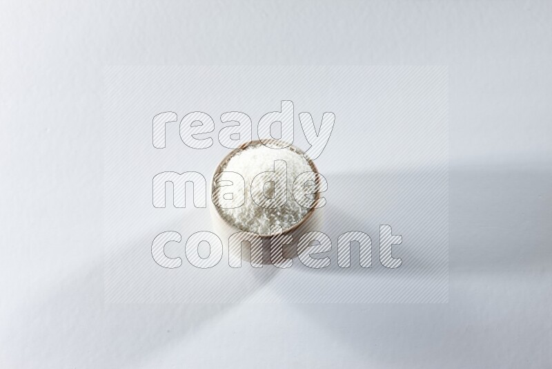 A beige ceramic bowl full of desiccated coconut on a white background in different angles