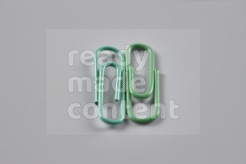 Green paper clips isolated on a grey background
