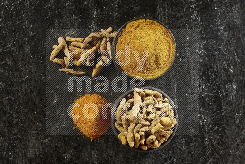 وعاءان من الفخار باللون الأسود، أحدهما ممتلئ ببودرة الكركم والآخر ممتلئ بأصابع كاملة من الكركم المجفف على خلفية سوداء