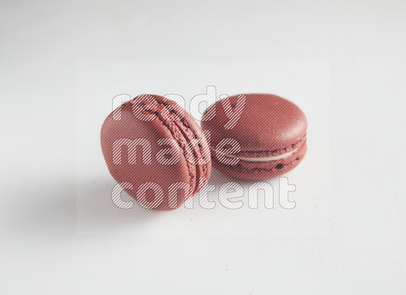 45º Shot of two Red Velvet macarons on white background