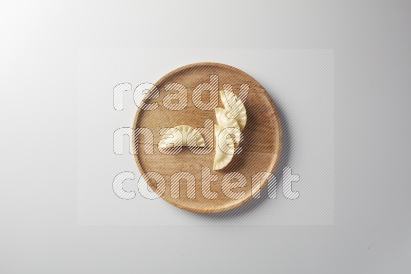 Four Sambosas on a wooden round plate on a white background