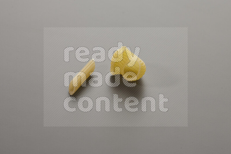 Mini penne pasta with other types of pasta on grey background