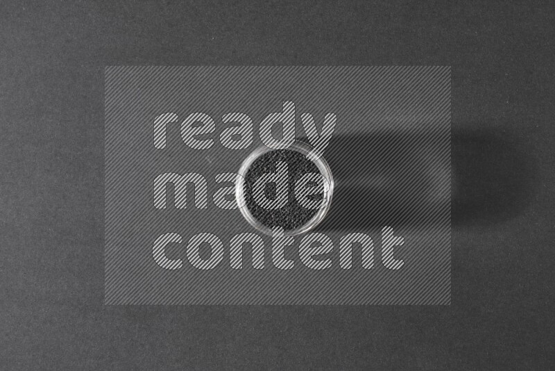 وعاء زجاجي ممتلئ ببذور حبة البركة علي خلفية سوداء