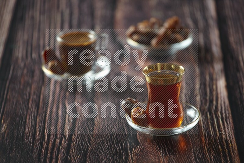 A tea glass cup with dates and coffee on wooden background