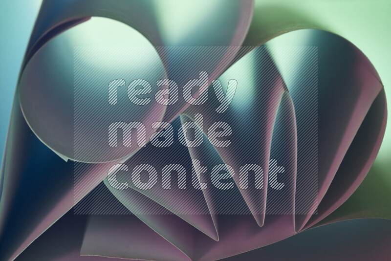 An artistic display of paper folds creating a harmonious blend of geometric shapes, highlighted by soft lighting in green and pink tones