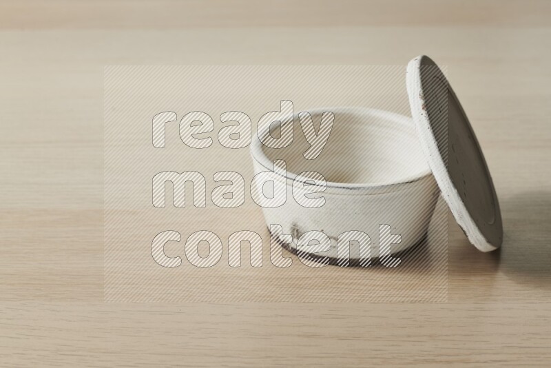 A white pottery bowl on light wooden background