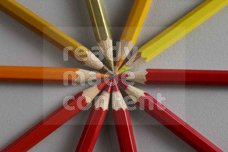 An arrangement of colored pencils in different colors on grey background