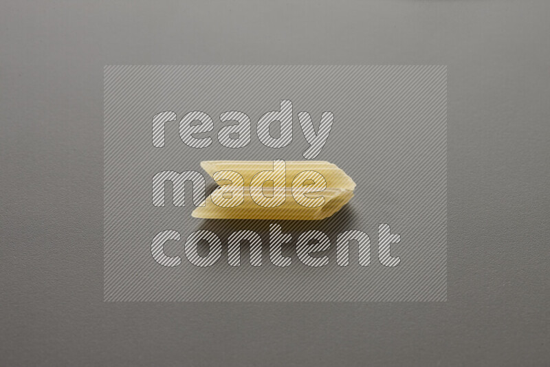 Mini penne pasta on grey background