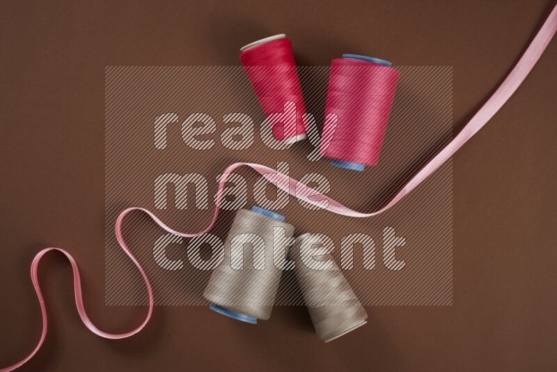 A pink collection of sewing and tailoring tools arranged on a brown background
