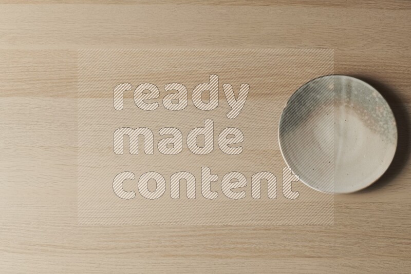 A multicolored pottery plate on light wooden background