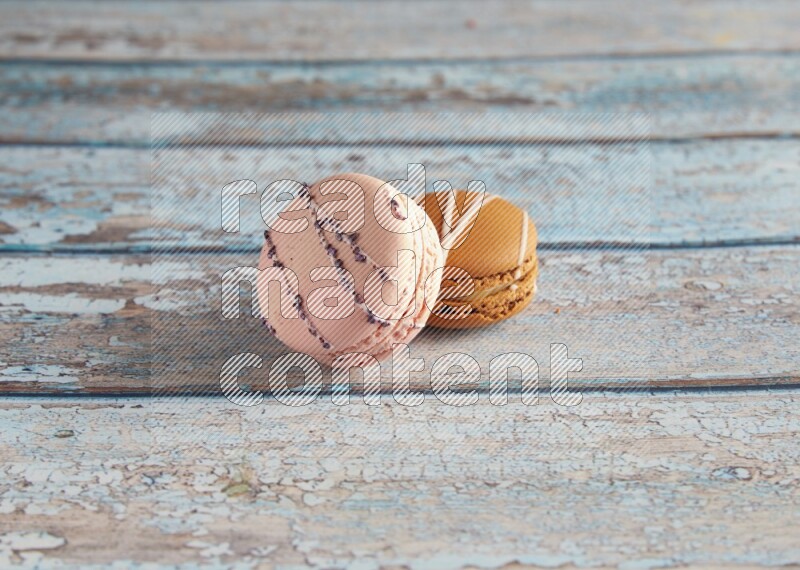 45º Shot of of two assorted Brown Irish Cream, and pink orange blossom  macarons on light blue background