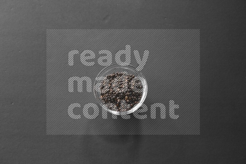 فلفل أسود في وعاء زجاجي علي خلفية سوداء