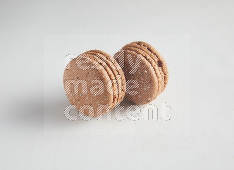 45º Shot of two Brown Hazelnuts macarons on white background
