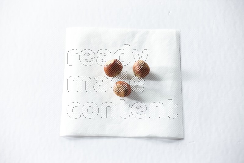 3 hazelnuts on a piece of paper on a white background in different angles